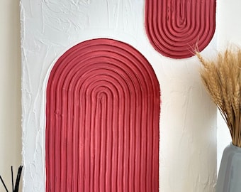 May include: Abstract art painting with two red arches on a white textured background. The arches are made of raised lines.