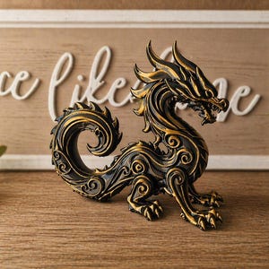 May include: A black and gold dragon figurine with intricate details. The dragon is posed with its head up and tail curled. The figurine is on a wooden surface, with a decorative sign in the background that says "Love Like Me".
