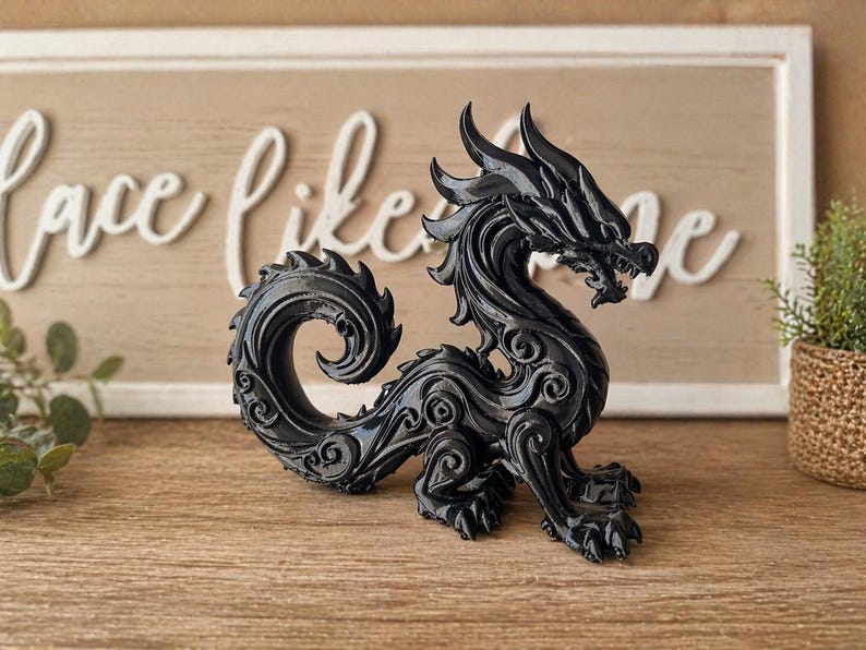 May include: A black dragon figurine with intricate details, including scales, horns, and a curled tail. The dragon is posed on a wooden surface, with a decorative sign in the background.