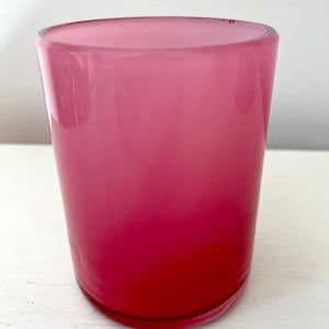 May include: A pink glass candle holder with a gradient from light pink to dark pink.