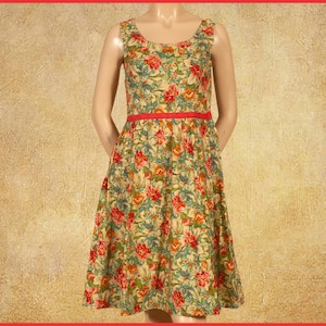 Peut inclure: Robe sans manches à imprimé floral avec encolure arrondie et ceinture rouge. La robe présente un fond beige avec des motifs floraux rouges, oranges et verts. La jupe s'évase à partir de la taille.