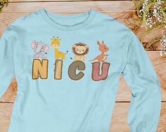 Può includere: Maglietta a maniche lunghe blu chiaro con una grafica di una giraffa, un elefante, un leone e un canguro. Il testo "NICU" è stampato in lettere marroni, grigie e rosa.