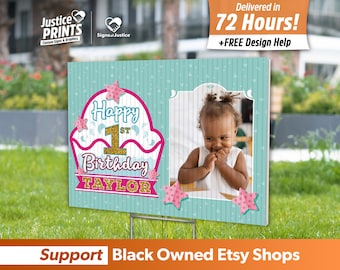 May include: A teal blue and pink birthday sign with a cupcake design and the text "Happy 1st Birthday TAYLOR". A photo of a child is in the upper right corner of the sign.
