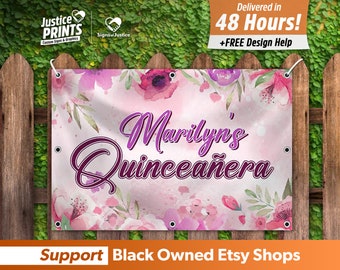 May include: A pink and purple floral design banner with the text "Marilyn's Quinceañera" in a purple script font. The banner is hanging on a wooden fence.