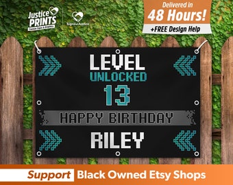 May include: Black banner with white text that reads "LEVEL UNLOCKED 13 HAPPY BIRTHDAY RILEY". The banner has pixelated arrow designs and is hanging on a wooden fence. The banner also says "Support Black Owned Etsy Shops".
