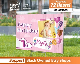 May include: A pink and white birthday yard sign with the text "Happy Birthday" and "1st". It features a photo of a child and cartoon balloons. The sign also includes the name "Kyle".