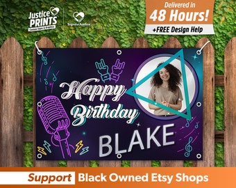 May include: A personalized birthday banner with a photo of a person, the name "BLAKE", and the text "Happy Birthday". The banner has a dark blue and purple background with musical notes and a microphone graphic. The banner is hanging on a wooden fence.