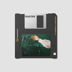 Puede incluir: Disquete negro con texto plateado y blanco que dice "MASTER AGFA EMULATIONS". El disco también tiene el texto "SHOOT DIGITAL. LOOK LIKE FILM." y "20 PRESETS, 3 PROFILES." Se ve una mano con una manga transparente.