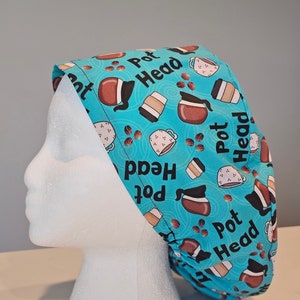 May include: A teal surgical scrub cap with a repeating pattern of coffee pots, coffee cups, and coffee beans. The words "Pot Head" are printed on the cap in white. The cap is displayed on a white mannequin head.