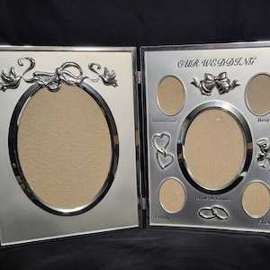 Könnte beinhalten: Silberfarbener Bilderrahmen mit Scharnier. Der Rahmen hat acht ovale Öffnungen für Fotos. Der Rahmen ist mit Tauben, einer Schleife und Hochzeitssymbolen verziert. Der Rahmen trägt den Text "Our Wedding" oben.