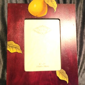 May include: A dark red wooden picture frame with a painted pear and leaves design. The frame is 5 inches by 7 inches (13 cm by 18 cm).