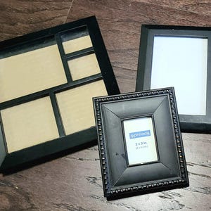 Könnte beinhalten: Drei schwarze Bilderrahmen, einer mit mehreren Öffnungen und zwei mit einer einzigen Öffnung. Der kleinere Rahmen trägt den Text "Pinnacle 2 x 3 Zoll (5,1 x 7,6 cm)"
