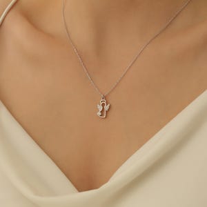 Puede incluir: Un collar de plata con un delicado colgante de &aacute;ngel con peque&ntilde;as piedras transparentes. El colgante es un simple contorno de un &aacute;ngel con alas.