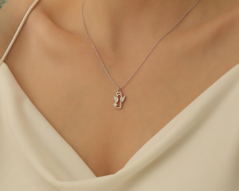 Puede incluir: Un collar de plata con un peque&ntilde;o colgante de &aacute;ngel con halo y alas. El &aacute;ngel est&aacute; contorneado con peque&ntilde;as piedras transparentes.