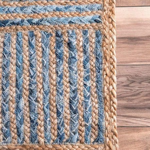 May include: A rectangular area rug featuring a braided construction of natural tan jute fibers and strips of blue denim fabric. The design incorporates alternating horizontal and vertical striped patterns, finished with a thick braided jute border.