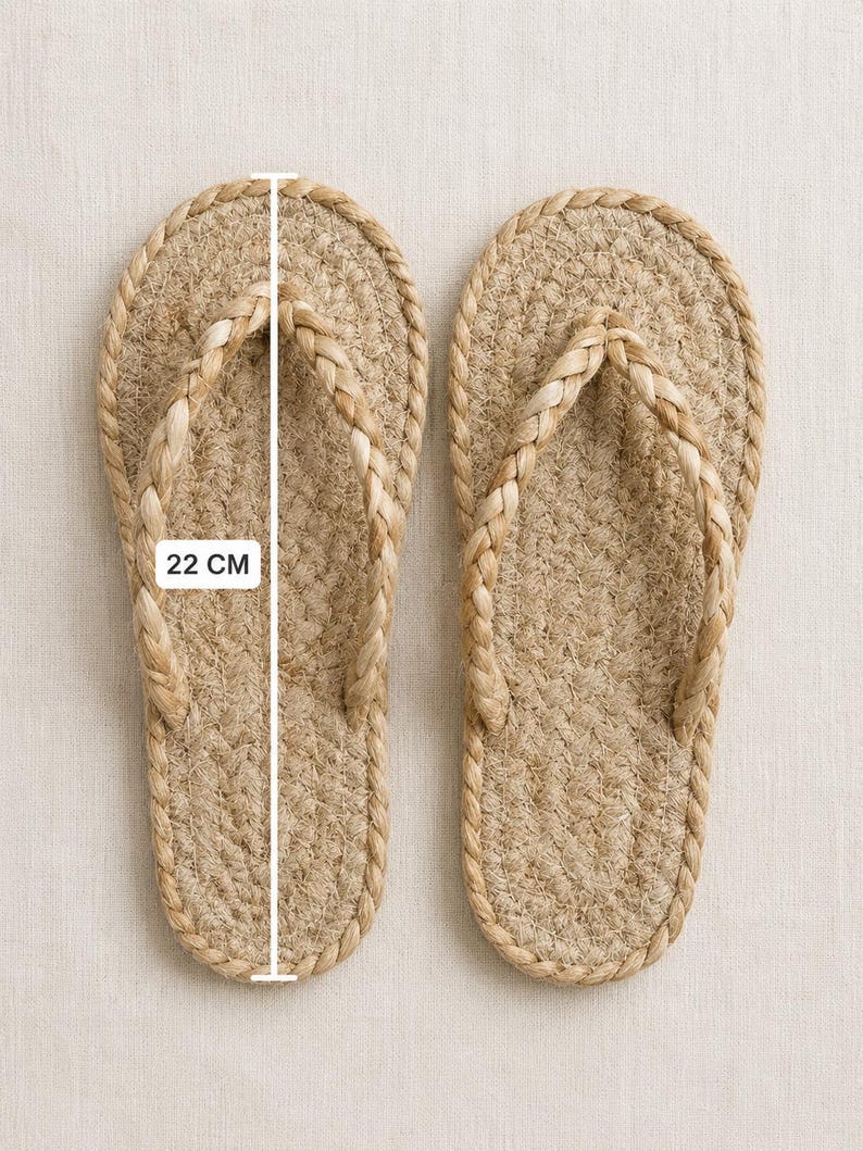 May include: A pair of tan flip-flops crafted from braided natural fiber rope. The sandals feature a woven sole and a braided strap design. A white measurement line is overlaid on the left sandal, clearly indicating a length of 22 cm.