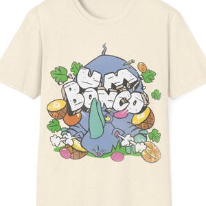 Könnte beinhalten: Cremefarbenes T-Shirt mit einer skurrilen Grafik. Das Design zeigt ein blaues Nashorn, den Text "Um Bongo" und verschiedene Früchte. Das Kunstwerk hat einen verspielten, cartoonartigen Stil mit leuchtenden Farben und kräftigen Umrissen.