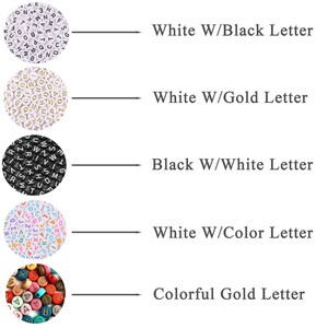 Op de afbeelding: Vijf rijen alfabet kralen in verschillende kleuren en lettertypen. De eerste rij toont witte kralen met zwarte letters. De tweede rij toont witte kralen met gouden letters. De derde rij toont zwarte kralen met witte letters. De vierde rij toont witte kralen met kleurrijke letters. De vijfde rij toont kleurrijke kralen met gouden letters.
