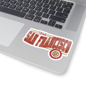 May include: A red and gold vintage sticker with the text "1946 SAN FRANCISCO FOOTBALL TEAM" in a retro font. The sticker has a distressed look and a circular seal with a football helmet graphic.
