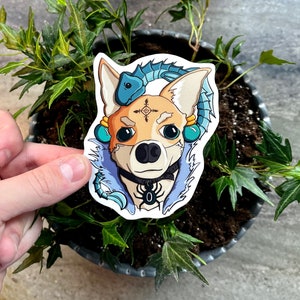 May include: A sticker of a cartoon chihuahua wearing a blue and teal fur coat with a scorpion on its chest. The chihuahua has a blue and teal scorpion on its head and is wearing a black choker with a silver charm.