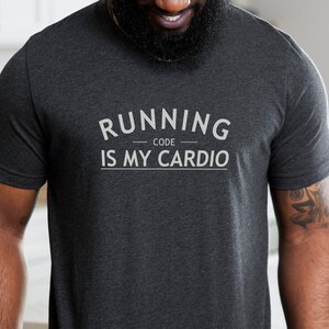Pode incluir: Uma camiseta cinza escura com o texto "RUNNING CODE IS MY CARDIO" impresso em branco.