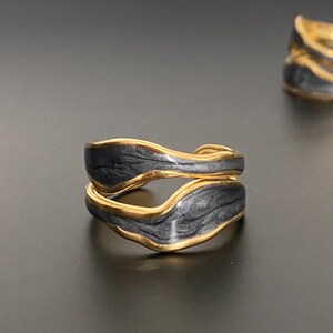 Puede incluir: Dos anillos de oro con esmalte negro. Los anillos están diseñados con una forma ondulada y orgánica.
