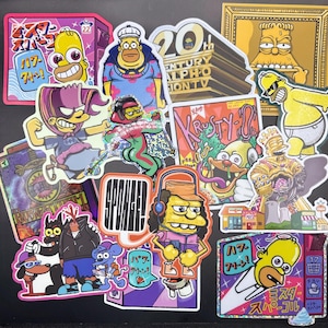 May include: A collection of colorful stickers featuring cartoon characters in various poses and styles. The stickers include images of Homer Simpson, Bart Simpson, and other characters, with Japanese text and vibrant designs. The stickers are on a black background.
