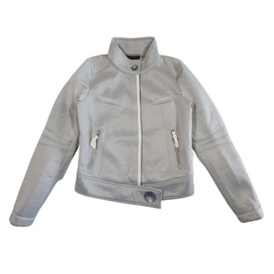 Peut inclure: Veste de moto gris clair avec un col montant, une fermeture éclair blanche et deux poches zippées. La veste a une fermeture boutonnée à la taille et des détails matelassés sur les épaules et les manches.