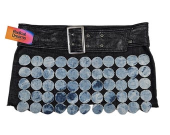 May include: Black denim skirt with a leather belt and silver buckle. The skirt is decorated with light blue denim circles. A tag with the text "Radical Dreams" is attached.