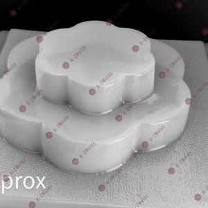 Puede incluir: Un molde blanco con forma de flor para manualidades. El molde está hecho de un material translúcido y tiene un diseño en capas. El texto "2.5L approx" es visible en la parte inferior izquierda. Este molde se utiliza para crear objetos decorativos.