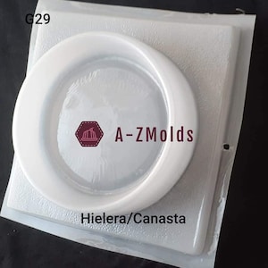 May include: A clear, circular mold with a raised rim, packaged in a clear plastic sleeve. The mold has the text "A-ZMolds" and "Hielera/Canasta" printed on it. The mold is designed for crafting.