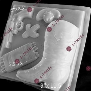 May include: A white plastic mold for making cowboy-themed cake decorations. The mold includes a cowboy boot, a gun, a bandana, and a cowboy hat. The mold measures 9 inches by 11.5 inches.
