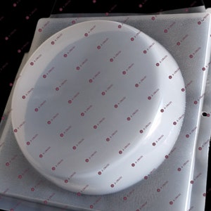 May include: A clear plastic mold for making a round cake or dessert. The mold is on a white surface.