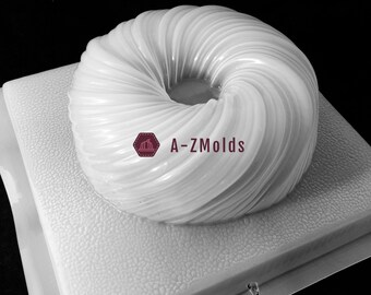 May include: A white, ring-shaped mould with a spiral design, sitting on a textured square base. The mould has a smooth, glossy finish. The text "A-ZMOlds" is visible on the image.