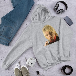May include: A gray hooded sweatshirt with a pocket featuring a printed image of a person with blonde hair, wearing a red scarf and a black jacket, looking at the camera.