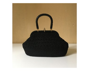 May include: A black crocheted handbag with a black plastic handle and a gold clasp.