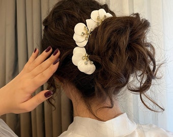 Un impresionante look de boda con elegantes accesorios para el cabello de novia florales blancos en 3D hechos de flores de arcilla hechas a mano - Postizos de boda hechos a mano