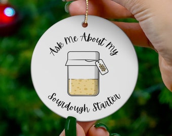 May include: White ceramic Christmas ornament with a black and white illustration of a jar of sourdough starter. The ornament reads "Ask Me About My Sourdough Starter".