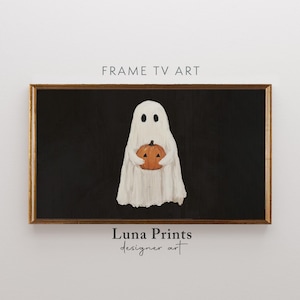 May include: A framed digital art print featuring a white ghost holding an orange pumpkin against a black background. The artwork has a vintage, textured appearance. The frame is a warm brown color. The text "FRAME TV ART" and "Luna Prints designer art" are visible.