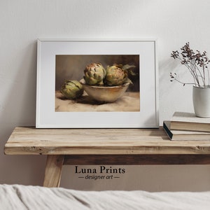 May include: A still life painting of three artichokes in a white bowl on a beige tablecloth. The artichokes are green and have a brown stem. The bowl is white and has a brown rim. The tablecloth is beige and has a brown pattern.