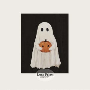 Peut inclure: Un fant&ocirc;me blanc tenant une citrouille orange en forme de jack-o'-lantern avec un visage triangulaire noir. Le fant&ocirc;me et la citrouille sont sur un fond noir. Luna Prints - designer art.