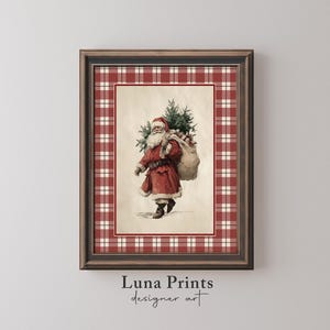 May include: A framed print with a vintage illustration of Santa Claus, carrying a sack and a Christmas tree. The artwork has a cream background and a red and white plaid border. The frame is dark brown. The text "Luna Prints designer art" is at the bottom.