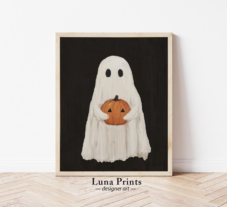 Peut inclure: Un fant&ocirc;me blanc tenant une citrouille orange en forme de jack-o'-lantern sur un fond noir. Le fant&ocirc;me a deux yeux noirs et un corps blanc en forme de drap. La citrouille a un visage sculpt&eacute; avec un nez triangulaire et deux yeux triangulaires. L'image est encadr&eacute;e dans un cadre en bois.