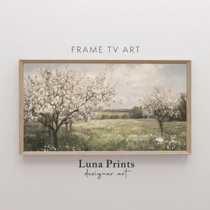 May include: A framed painting of a spring landscape with two trees in bloom. The trees are in the foreground with a field of green grass and white flowers in the background. The sky is a soft blue with white clouds.