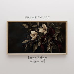 Könnte beinhalten: Ein gerahmter Druck eines dunklen Blumenarrangements mit weißen Magnolienblüten und einem burgunderfarbenen Band. Der Hintergrund ist dunkel, fast schwarz. Der Druck ist mit "Luna Prints designer art" betitelt.