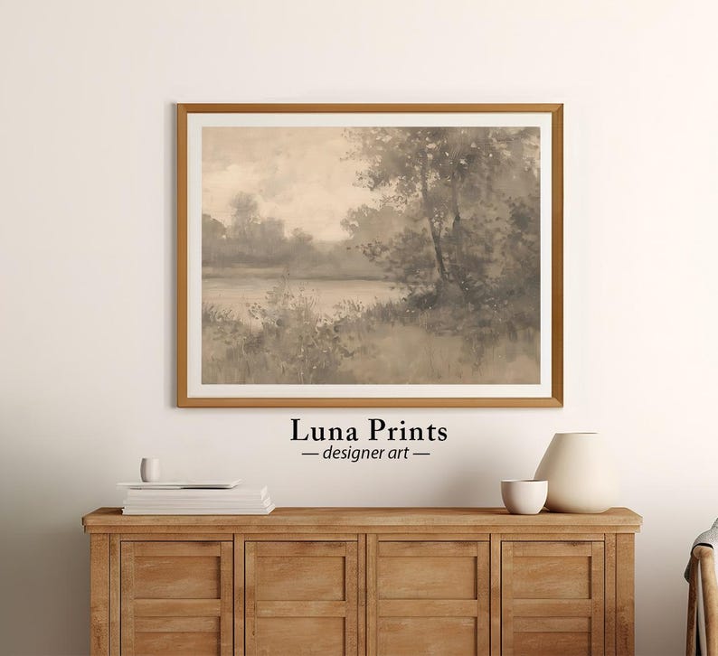 May include: A framed sepia-toned watercolor painting of a landscape with trees and a lake. The painting is in a wooden frame with a light brown finish. The painting is titled "Luna Prints - designer art".