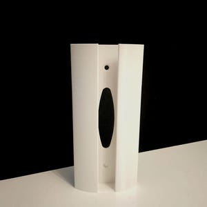 May include: White plastic wall mount with a slot for a dispenser. The mount has a small round hole and a larger oval hole.
