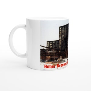 Puede incluir: Taza de cerámica blanca con una foto en blanco y negro de un edificio industrial. El texto "Haber Breaker, A" está impreso en rojo en la parte inferior de la taza.