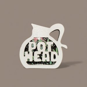 May include: White wooden decorative piece in the shape of a pitcher, with the words "POT HEAD" cut out. The inside of the pitcher features a colorful floral design with green leaves and red flowers.