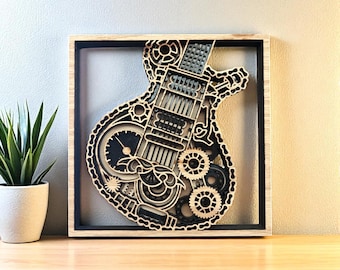 May include: A square wooden wall art piece featuring a layered, intricate cutout of an electric guitar silhouette. The design incorporates mechanical gear and chain motifs in contrasting black and natural wood tones, framed within a light wood border.